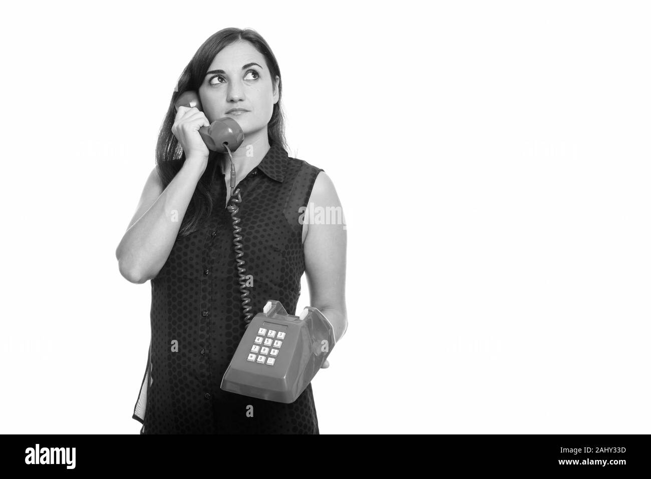 Studio shot of woman talking on vieux téléphone en pensant Banque D'Images
