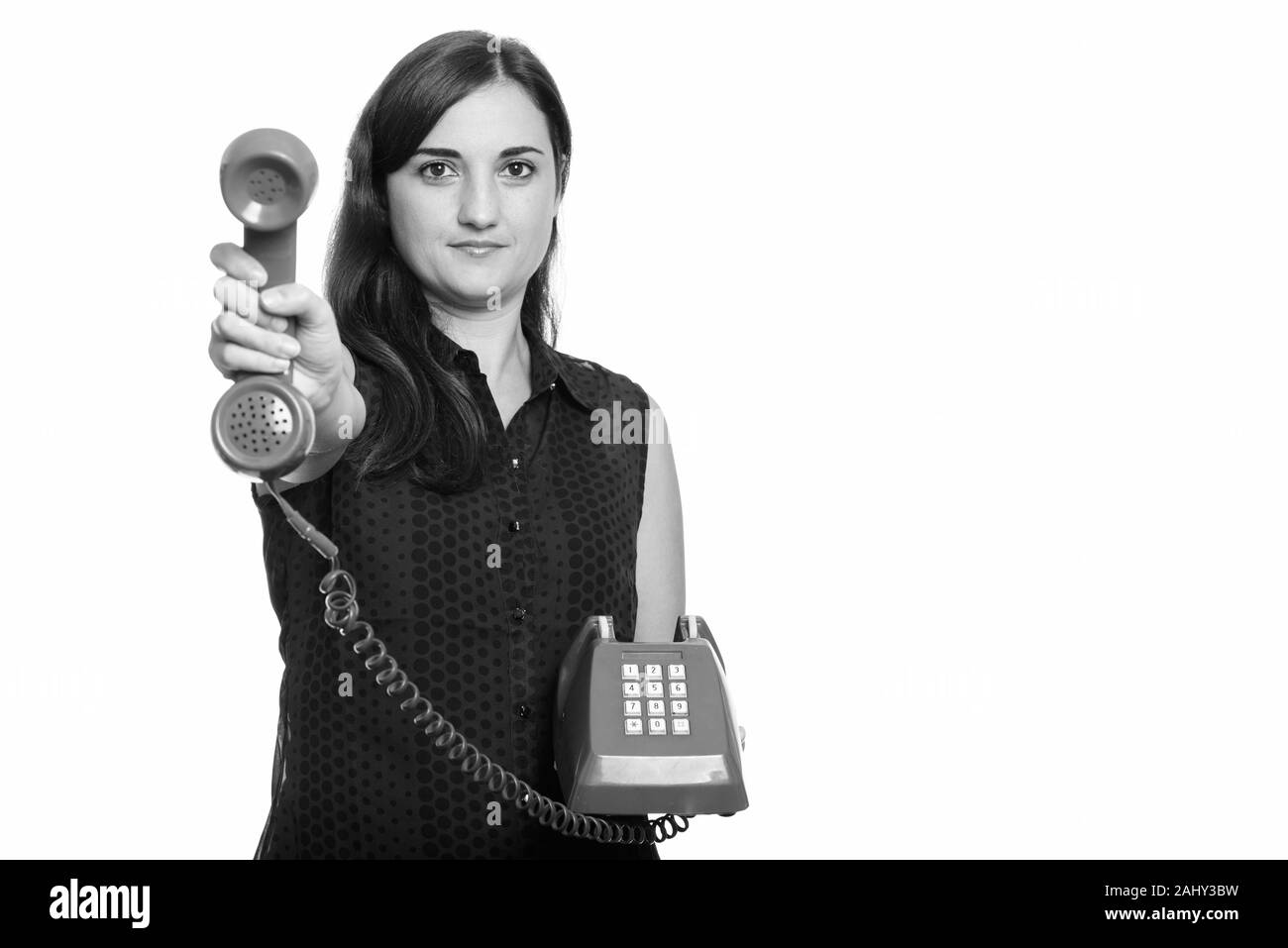 Studio shot of belle femme donner vieux téléphone Banque D'Images