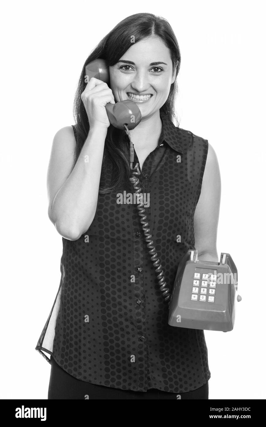 Studio shot of woman smiling while talking on old telephone Banque D'Images