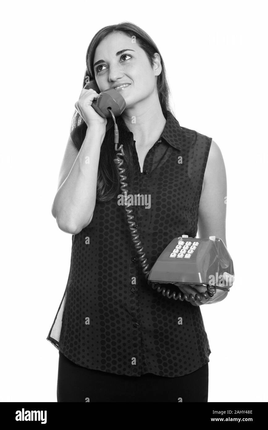 Thoughtful woman smiling while talking on old telephone Banque D'Images