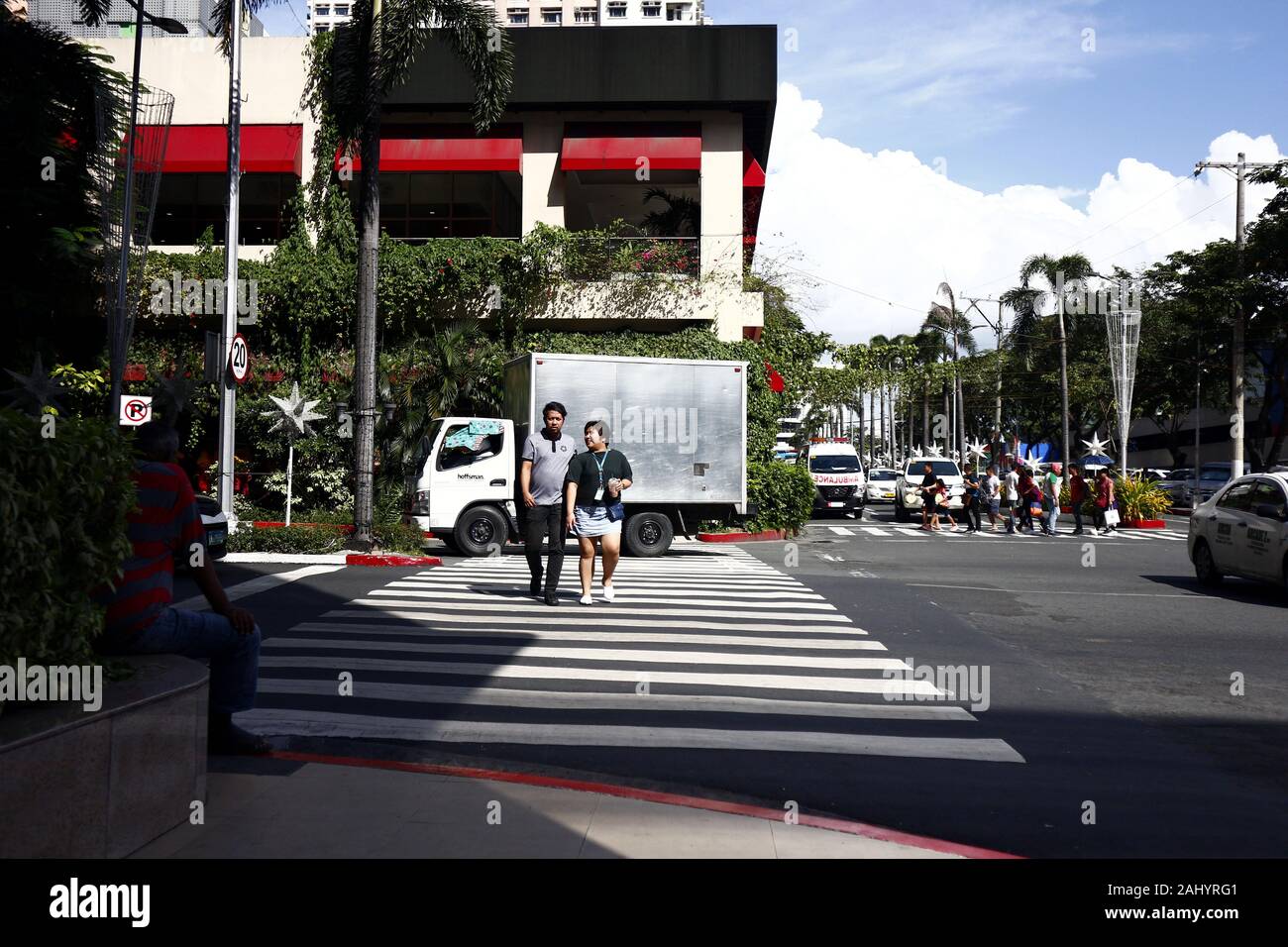 La ville de Quezon, Philippines - Le 27 décembre 2019 : les piétons traverser une intersection avec piétonnière à l'Araneta Center de Cubao, Quezon City. Banque D'Images