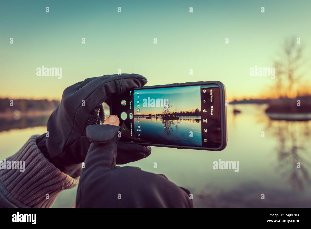 Par ailleurs les photographes avec des gants holding Smartphone et la prise de photo de petite île au cours beau coucher du soleil Banque D'Images