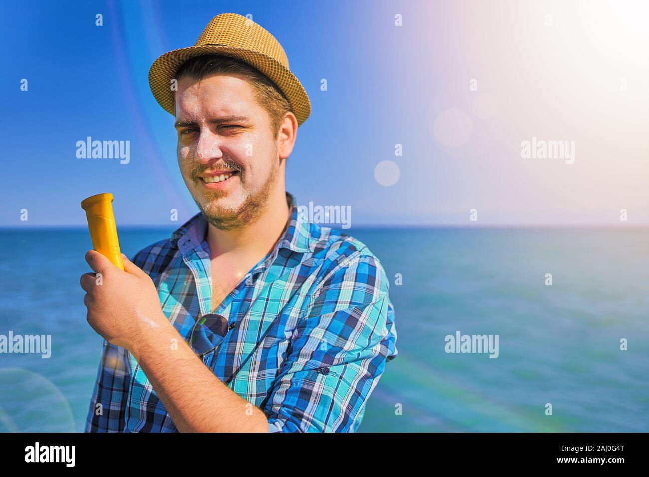 Guy mise sur crème solaire sur le visage. L'homme était tanné au soleil sur la mer, et il a utilisé l'écran solaire. Banque D'Images