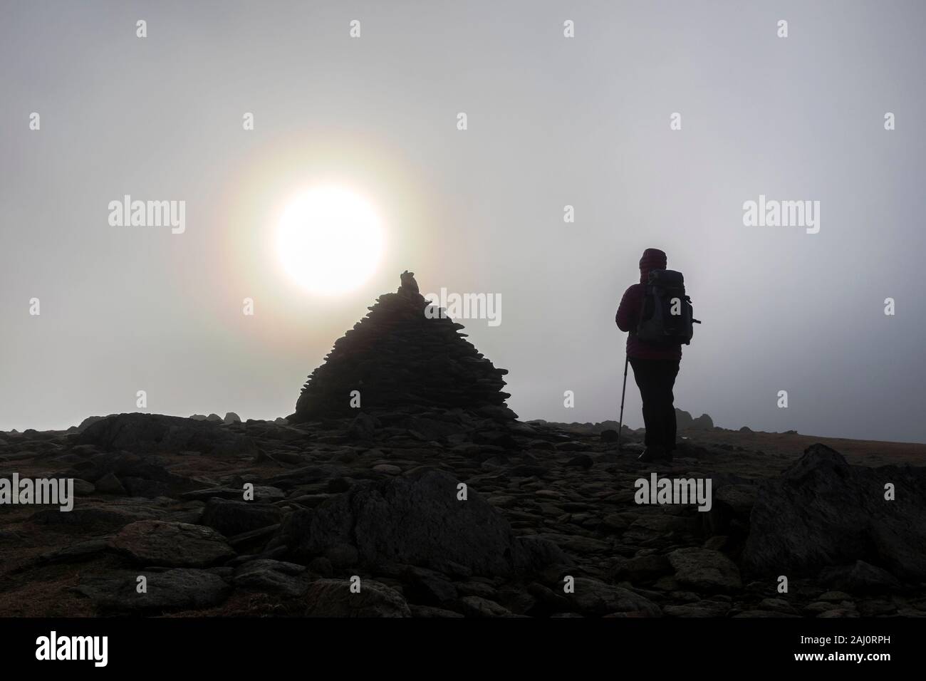 Walker sur le sommet du bord tombé comme les coups de soleil à travers les nuages, Coniston, Lake District, Cumbria, Royaume-Uni Banque D'Images