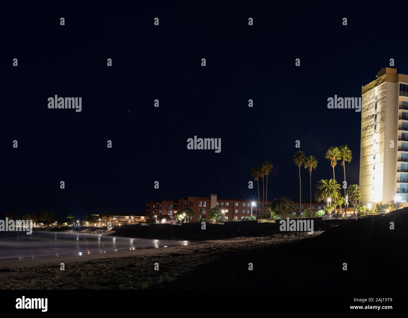 Hôtel de 11 étages éclairés par des lampes d'éclairage de nuit au-dessus des tours de condos et maisons qui bordent la promenade de la plage de Ventura riviera. Banque D'Images