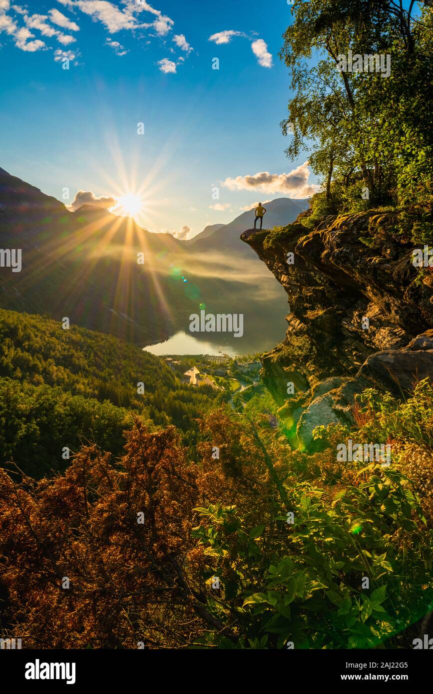 Vue arrière de l'homme sur le dessus des roches en admirant le coucher du soleil à Geiranger Stranda, municipalité, Sunnmore, More og Romsdal County, Norway, Scandinavia, Europe Banque D'Images