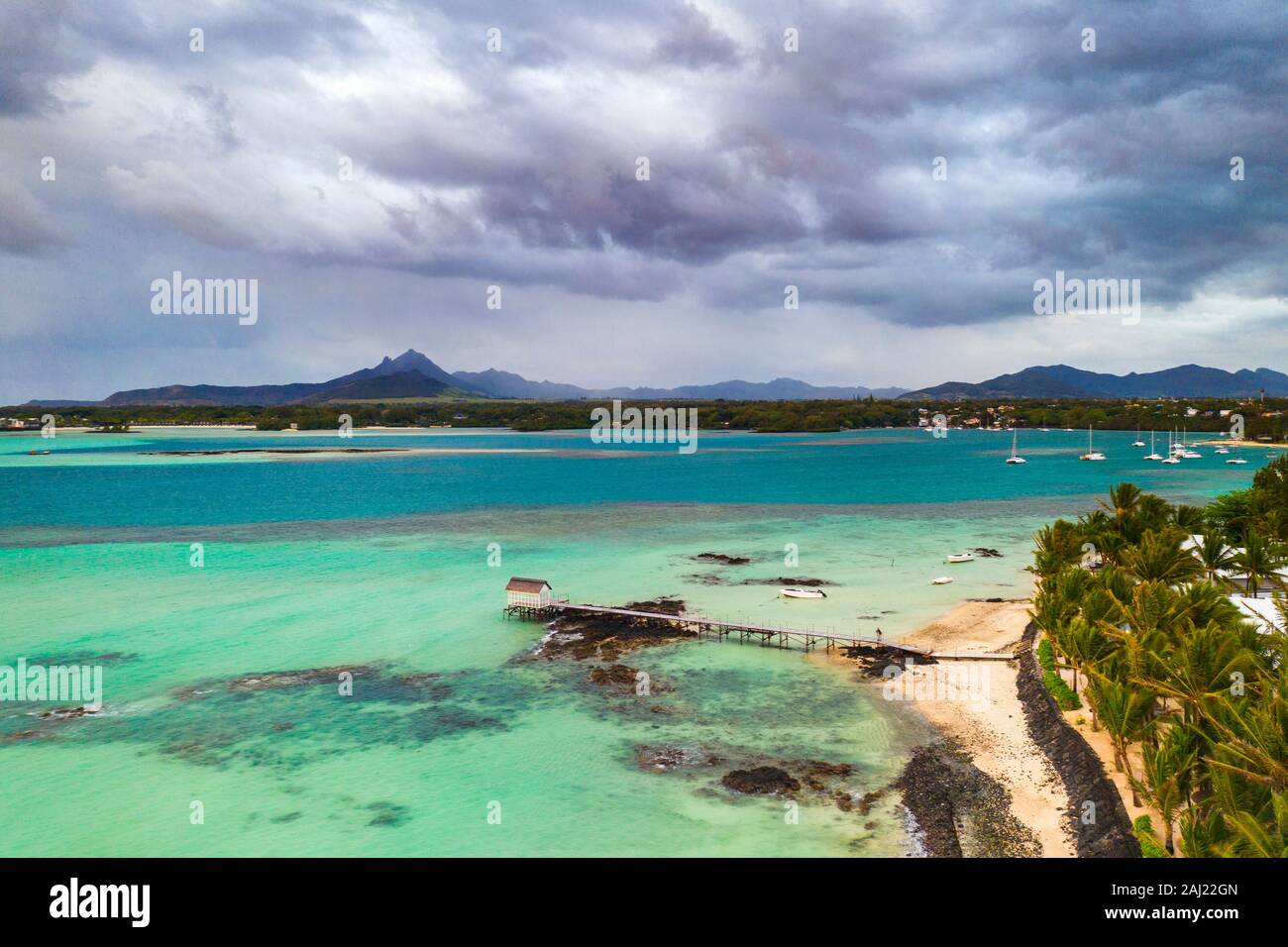 Nuages sur lagoon et de la jetée par une plage bordée de palmiers, vue aérienne, Trou d'Eau Douce, Flacq, côte est, l'Île Maurice, océan Indien, Afrique Banque D'Images