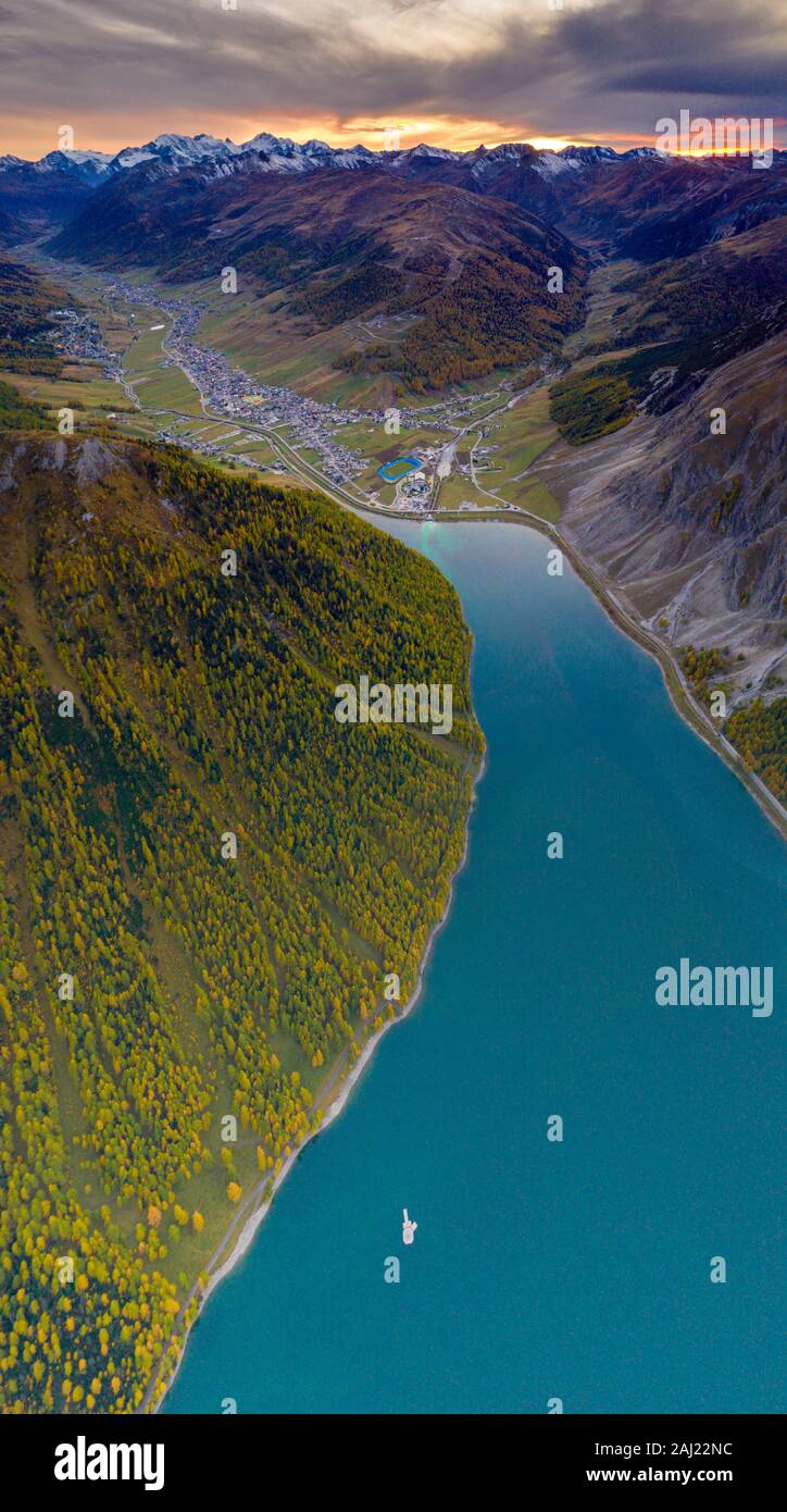 Vue panoramique aérienne de coucher de soleil sur Livigno et le mélèze arbres le long du lac en automne, province de Sondrio, Valtellina, Lombardie, Italie, Europe Banque D'Images