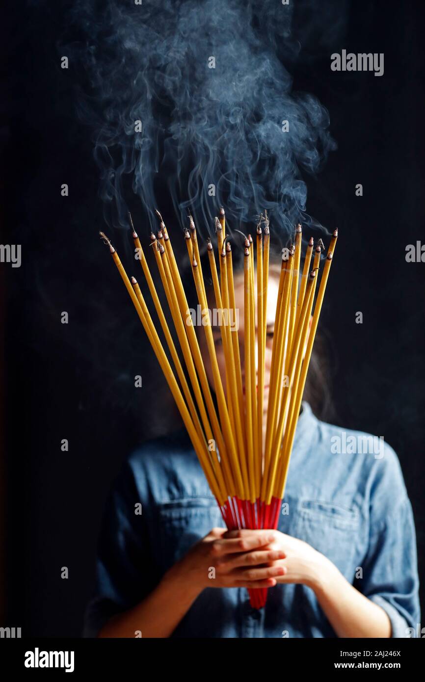Jeune femme chinoise en priant avec de grands bâtons d'encens brûlant dans ses mains, Ha Chuong Hoi Quan Pagode, Ho Chi Minh City, Vietnam, l'Indochine, l'Asie Banque D'Images