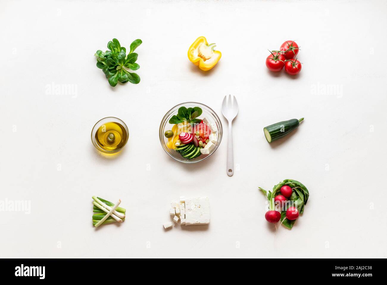 La préparation de salade grecque de légumes frais, fromage feta et d'huile d'olive. Voir ci-dessus de l'été dans un bol à salade et d'ingrédients. L'alimentation saine. Banque D'Images