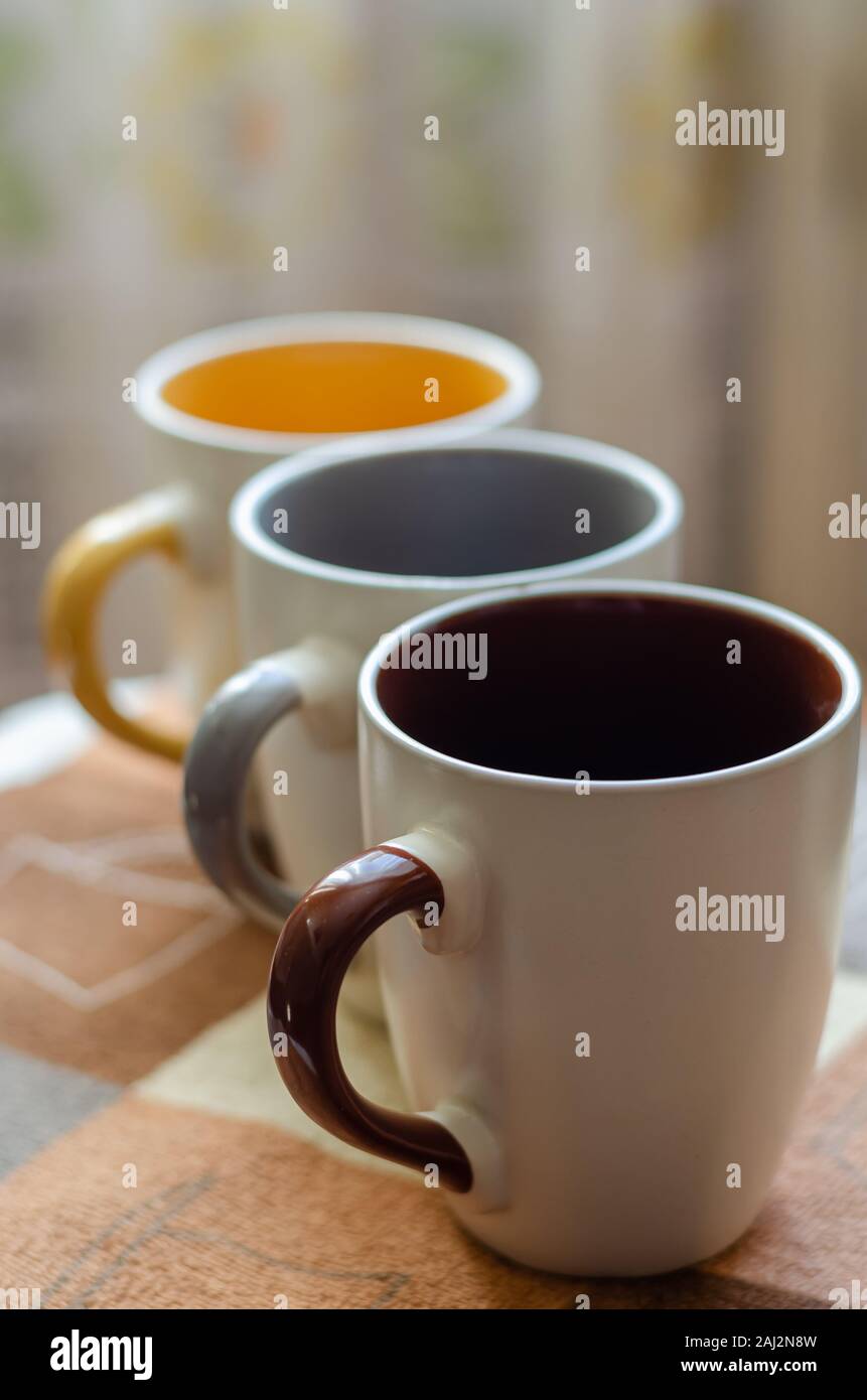 Un ensemble de tasses en céramique de couleurs différentes pour les trois membres de la famille. Les tasses sont alignés en diagonale. Close-up. Tir au niveau des yeux. Soft focus. Portrai Banque D'Images