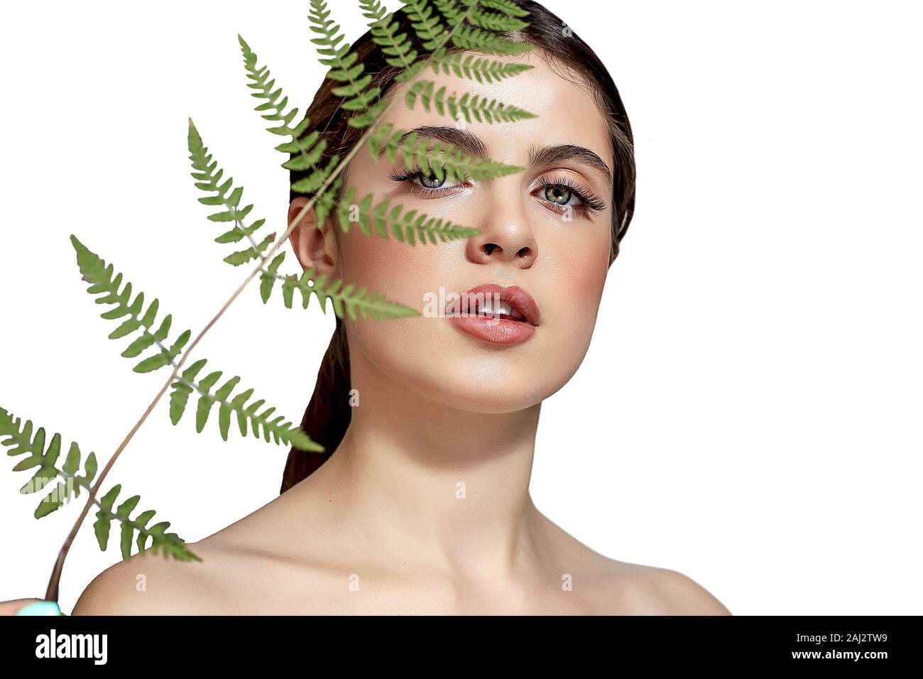 Portrait d'un adulte femme brune sur un fond blanc avec des soins de la peau, fougère vert concept, une belle peau et des mains avec manucure ongle. Banque D'Images