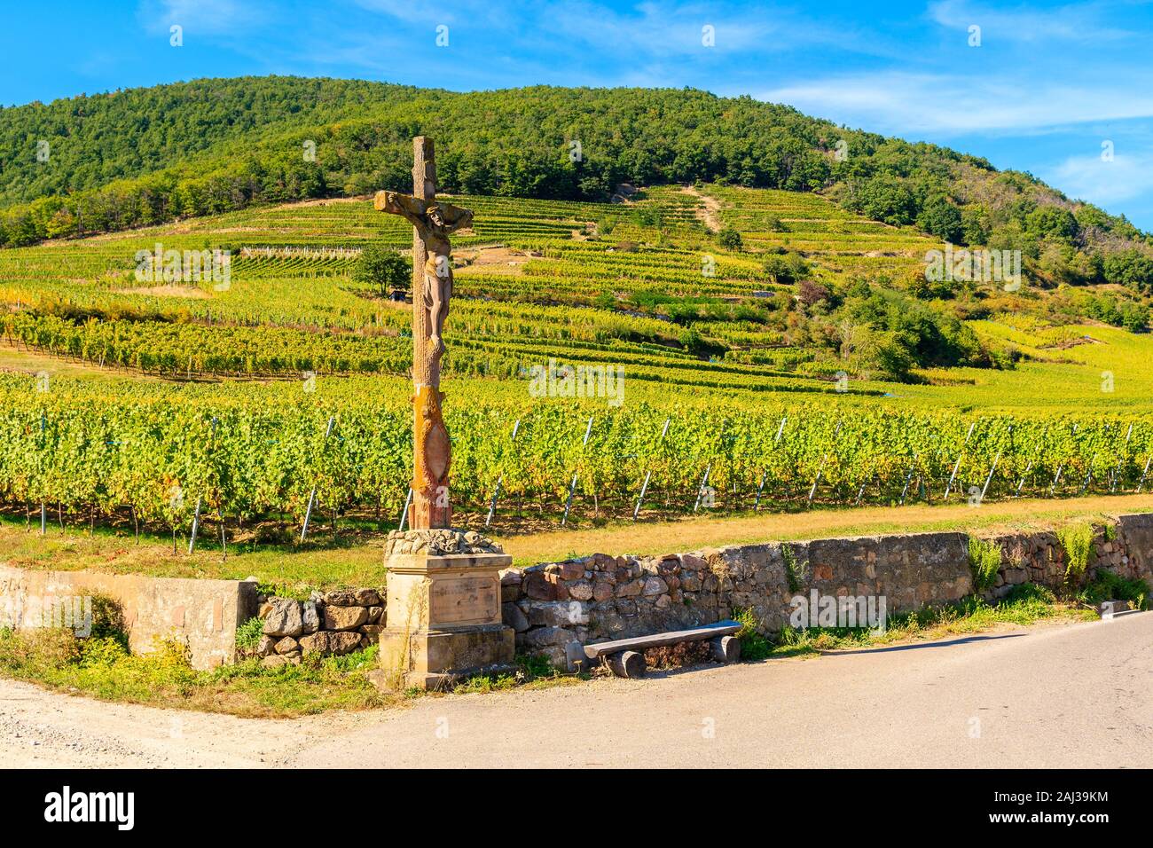 Jésus Christ statue en bois sur le cyclisme sur route le long de vignes à Kaysersberg village, Alsace, France Banque D'Images
