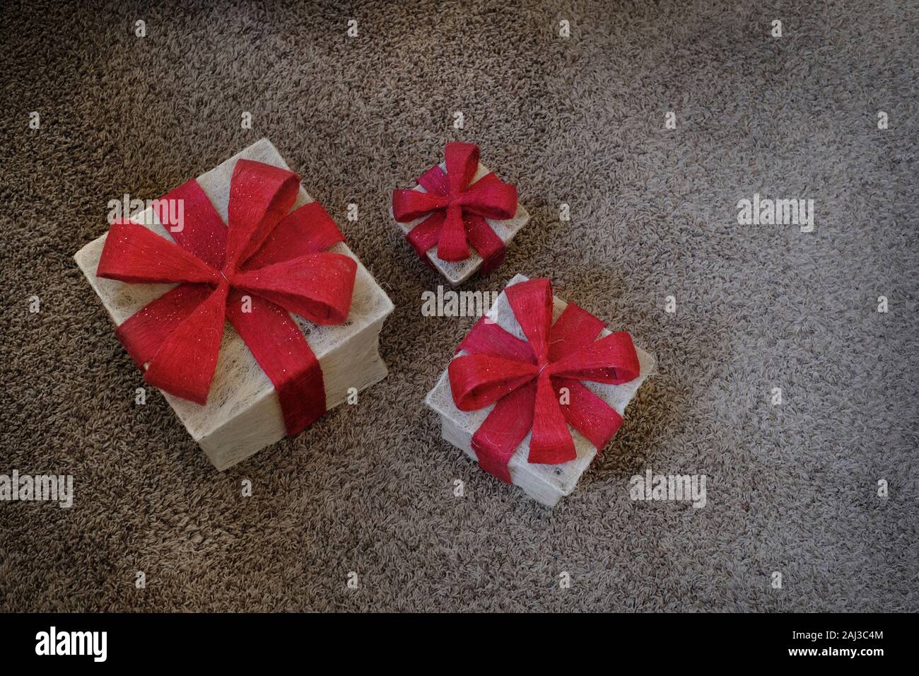 Cadeaux avec arcs rouge sur la moquette dans la maison pour les fêtes ou un anniversaire Banque D'Images
