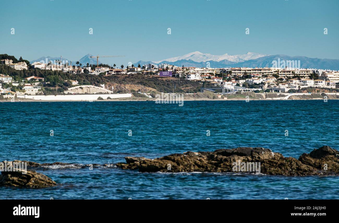 Littoral de Malaga vu de La Cala de Mijas plage un après-midi d'hiver ensoleillé avec le sommets blancs de la Sierra Nevada à l'horizon. Banque D'Images