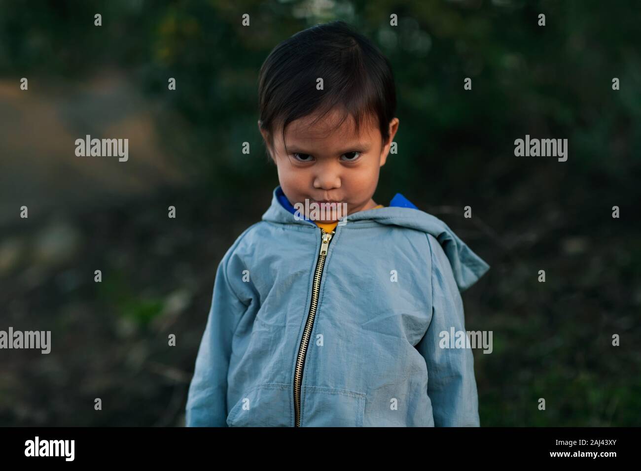 Un petit garçon dans une piscine avec une expression faciale qui semble négative récalcitrante et contrarié. Banque D'Images