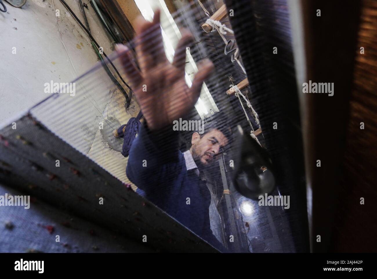 La ville de Gaza, en Palestine. 2 Jan, 2020. Un travailleur palestinien tisse des tapis sur un métier traditionnel en bois à une fabrique de tapis dans la ville de Gaza.Parler de vieille Gaza, et ce qui s'affiche sont des images d'argile poterie, verrerie colorée, mobilier en bambou et des métiers du bâti ancien tissage de tapis et tapis lumineux. Comme ces professions pourraient être en train de mourir dans le monde entier, le rythme de la baisse est trop rapide à Gaza que sur ses quelque 500 métiers, un seul est encore en activité. Credit : Mahmoud Issa/SOPA Images/ZUMA/Alamy Fil Live News Banque D'Images