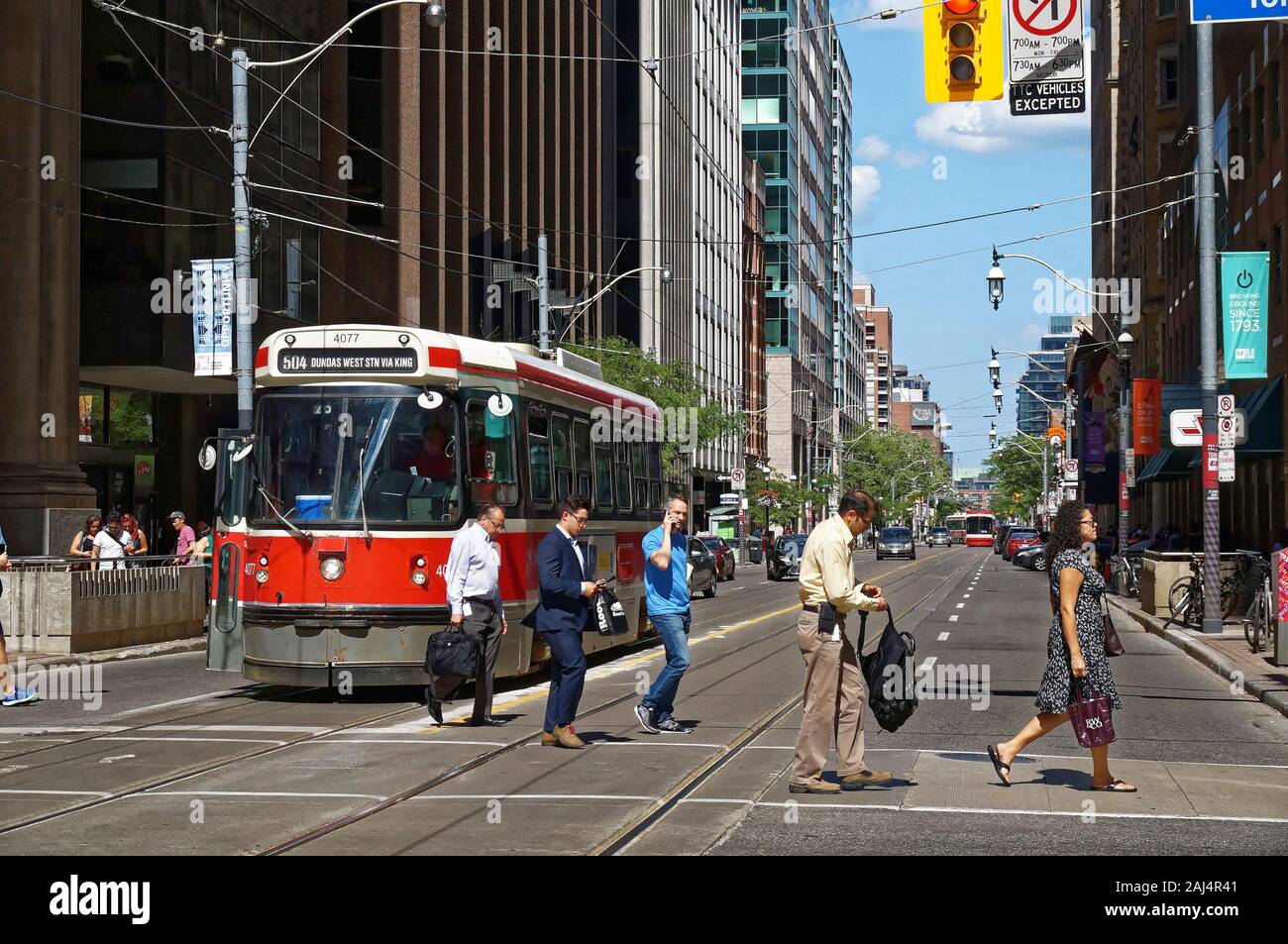 TORONTO, CANADA - 0627 2016 : les citadins de traverser la rue en face d'un vieux tramway sur King St Younge. intersection. Banque D'Images