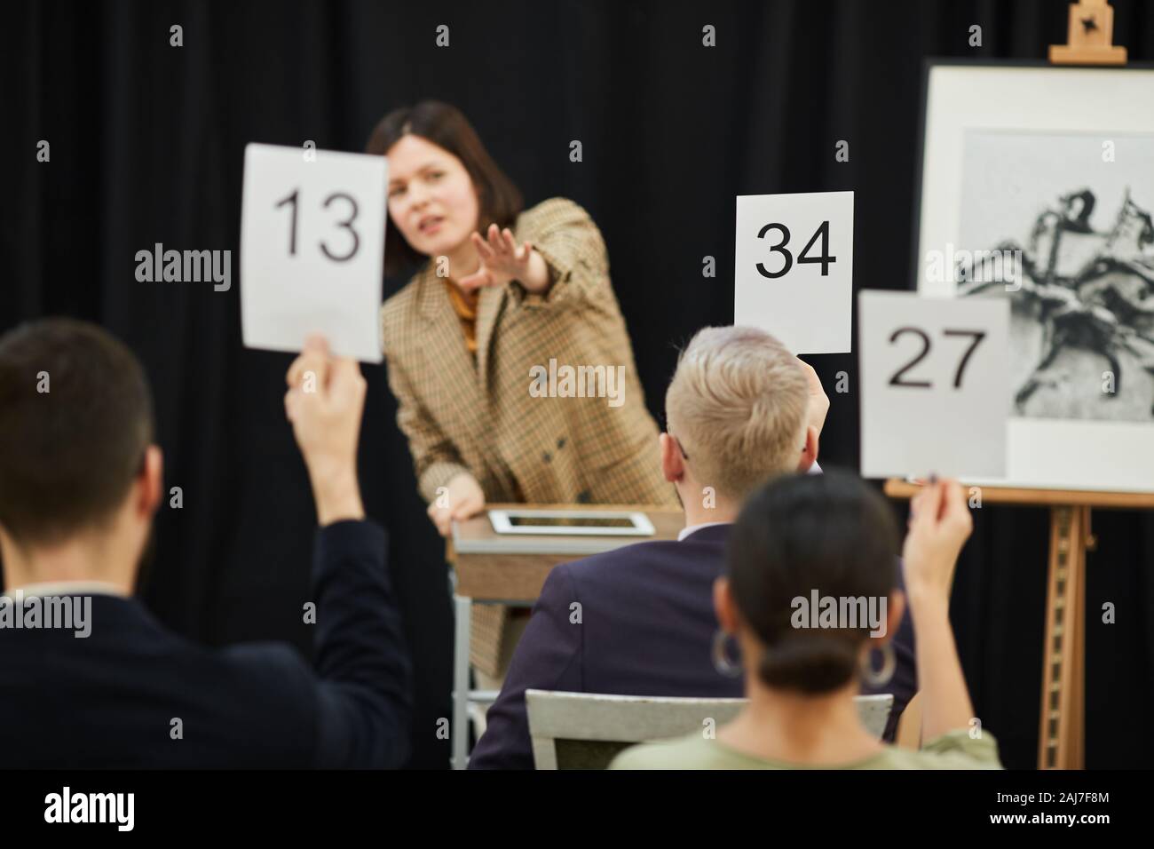 Vue arrière du jeune homme avec signe suggérant beaucoup d'argent pour le cadre d'une vente aux enchères d'art moderne Banque D'Images
