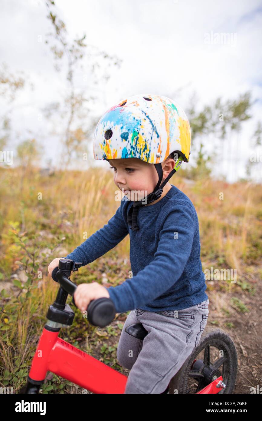 Vue latérale d'un jeune garçon en vélo rouge. Banque D'Images