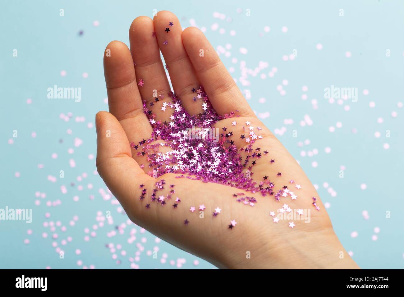 Woman's hand holding a pink glitter. Célébration, fête, anniversaire magic arrière-plan. Banque D'Images