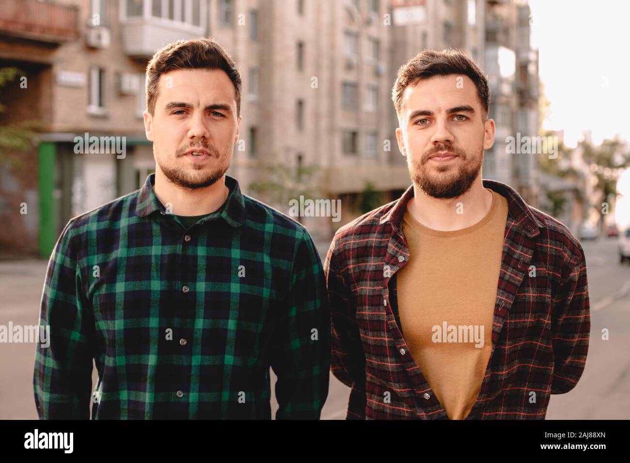 Portrait des frères jumeaux adultes debout dans la rue de la ville en été Banque D'Images