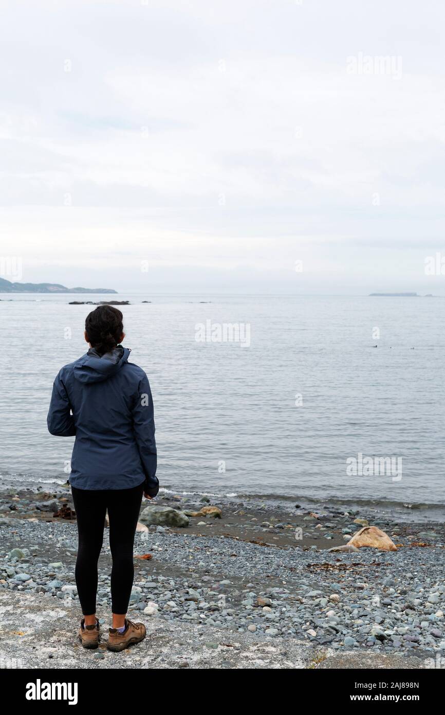 Femme regardant la mer à Witless Bay à Terre-Neuve et Labrador, Canada. La journée est couvert. Banque D'Images