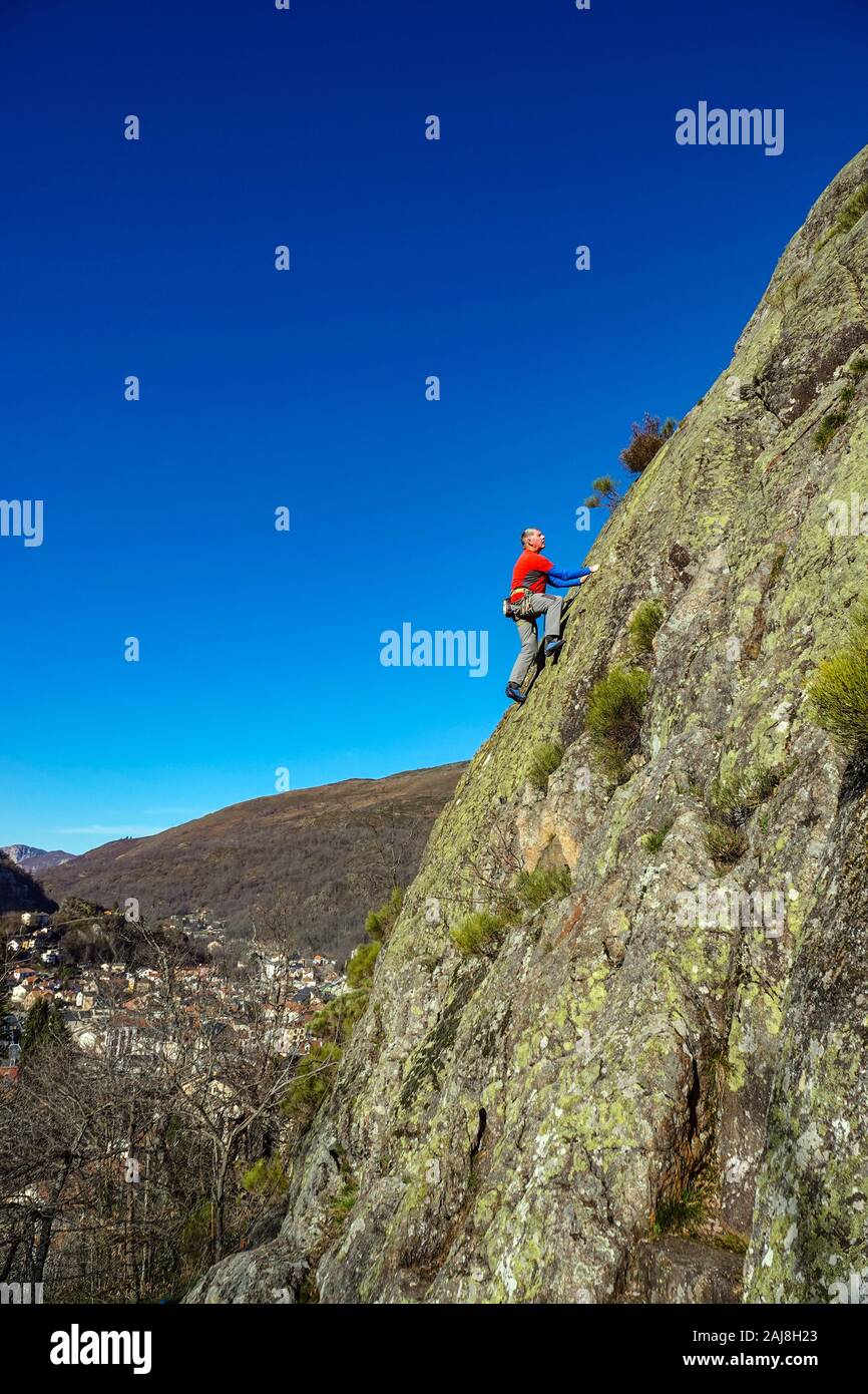 Male rock climber en rouge sur la falaise au-dessus de Ax les Thermes, Ariège, Pyrénées françaises Banque D'Images