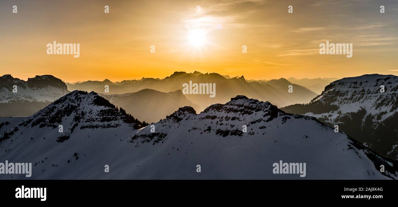 Lever du soleil dans les montagnes enneigées avec le brouillard et les faisceaux lumineux Banque D'Images