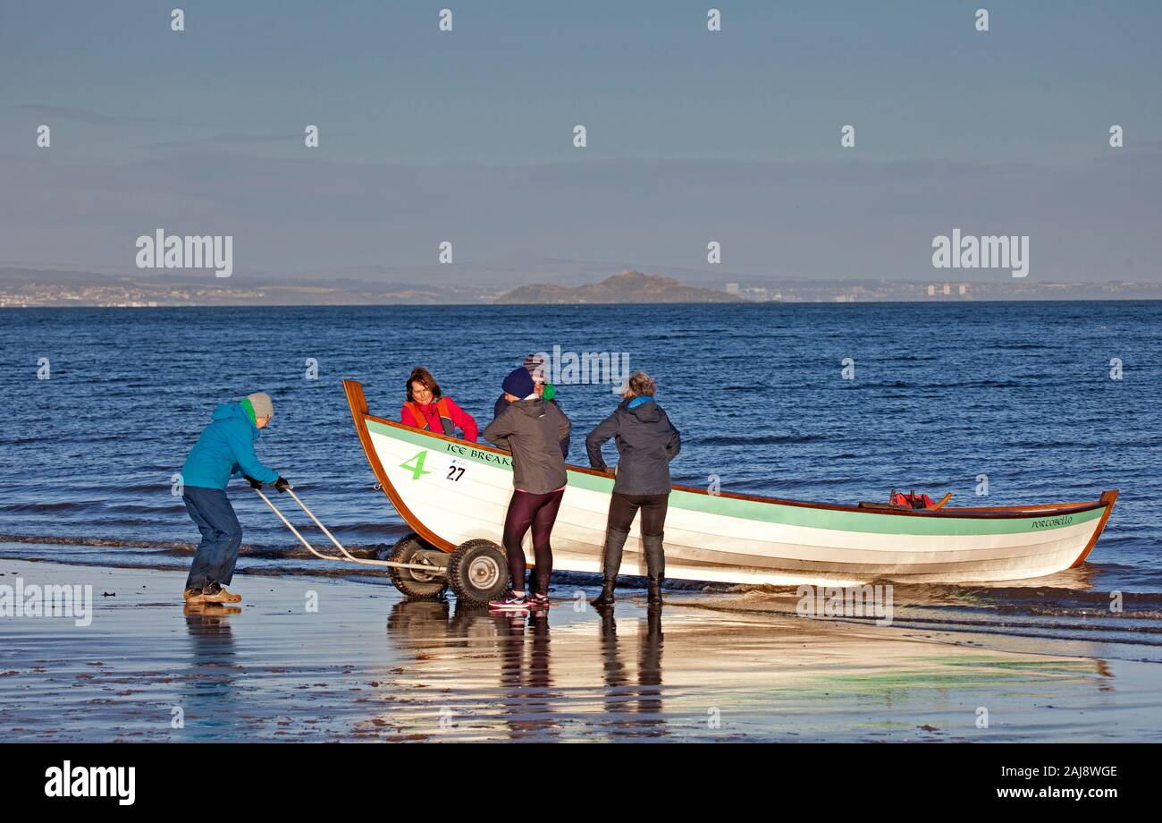 Portobello, Édimbourg, Écosse, Royaume-Uni. 3e janvier 2020. Météo 6°c personnes enveloppé pour la brise fraîche profiter de l'hiver soleil, toujours quelque chose à voir pour les familles à la plage de sable, comme l'équipe d'aviron de Portobello avec leur bateau le brise glace et les gens promènent leurs chiens certains portant des chauffe-corps pour protéger du froid. Banque D'Images