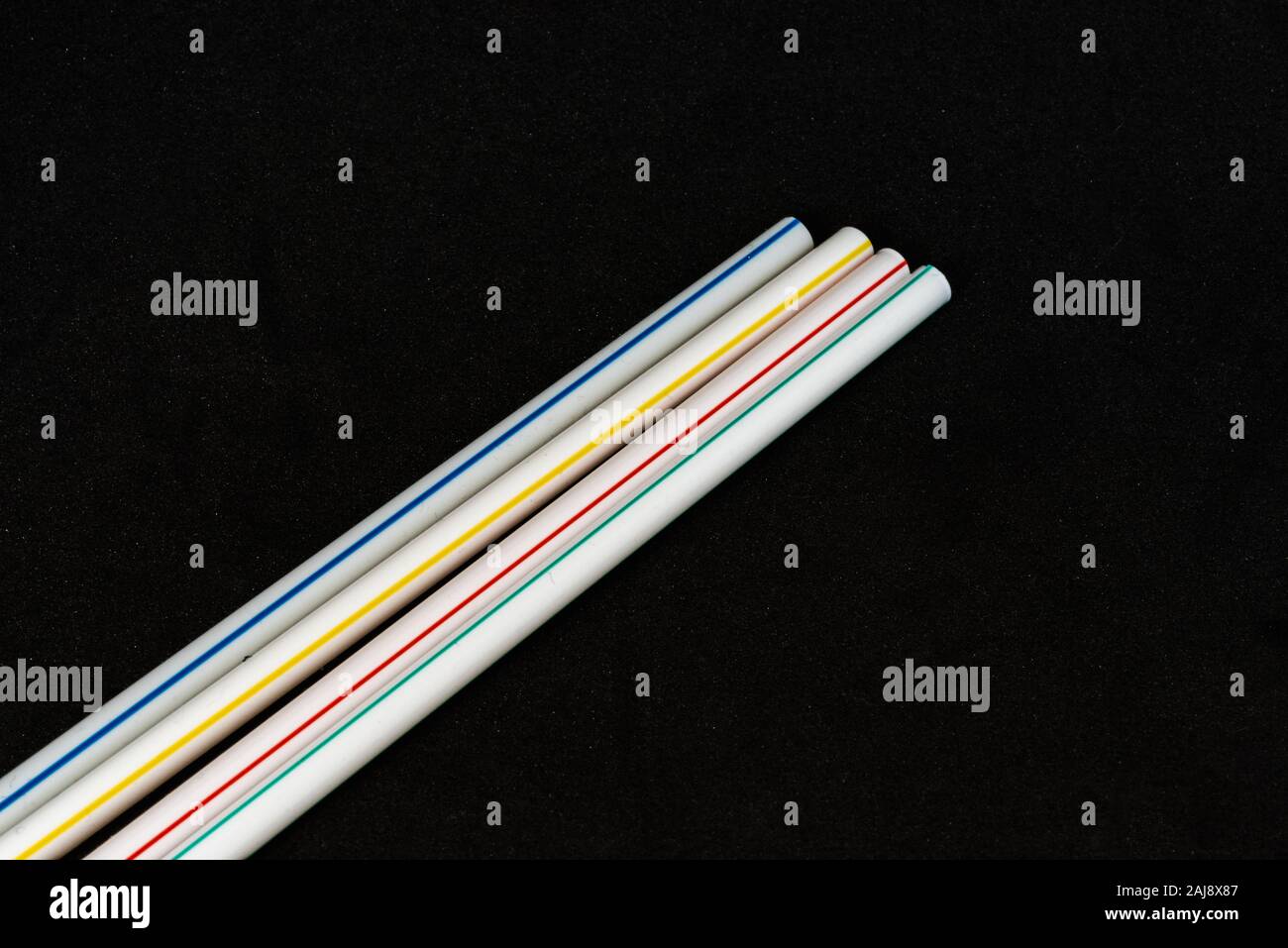 Des pailles en plastique blanc avec bandes de couleurs, matériaux polluants pour l'environnement Banque D'Images
