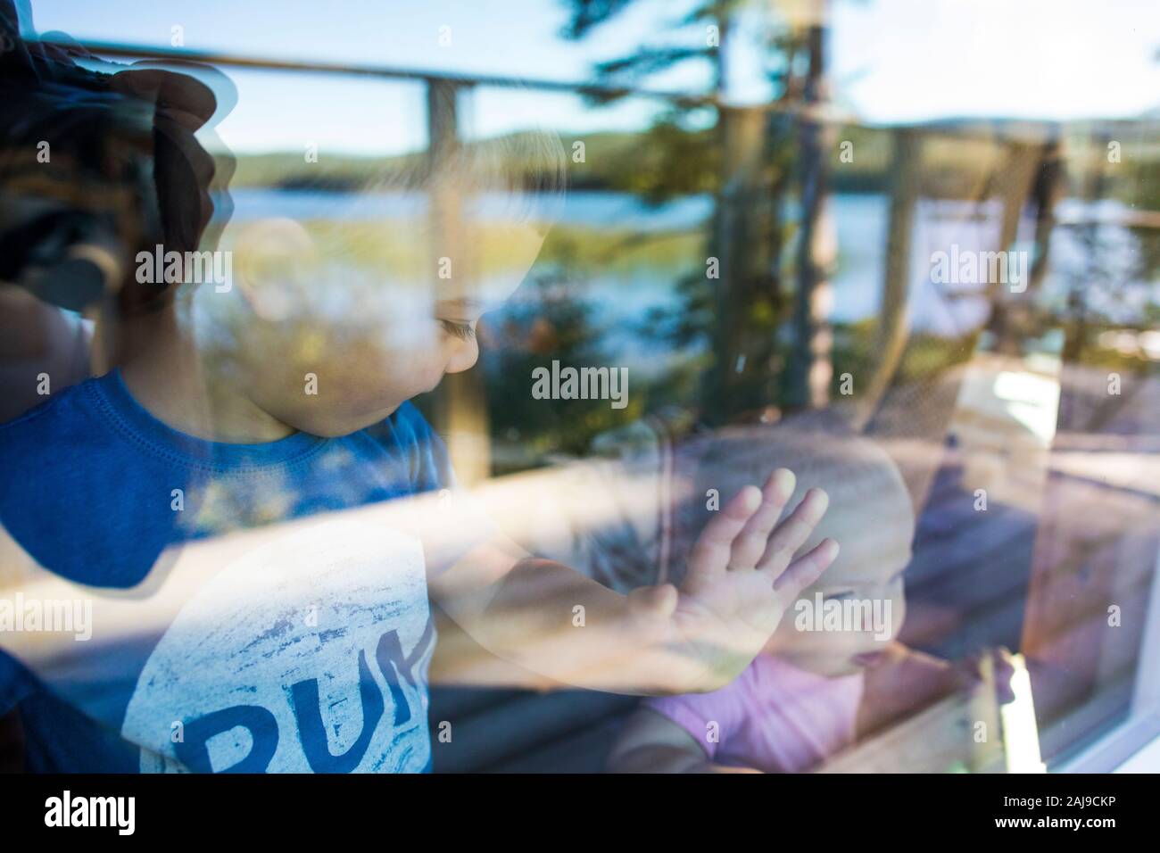 Vue de grand frère regardant vers le bas de bébé soeur par la fenêtre. Banque D'Images