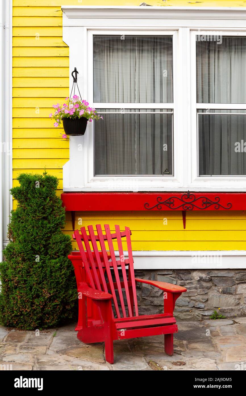 Chaise adirondack rouge à l'extérieur d'une maison à St John's, Terre-Neuve  et Labrador, Canada. La chambre est peinte en jaune Photo Stock - Alamy