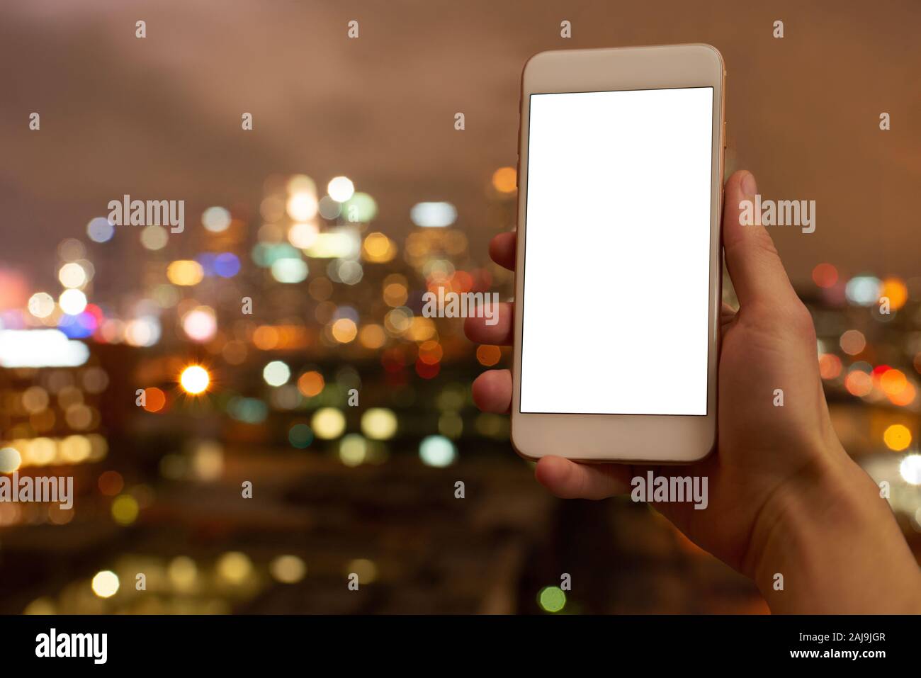 Main droite tenant un téléphone mobile avec écran vide, filtre flou lumières colorées en arrière-plan Banque D'Images