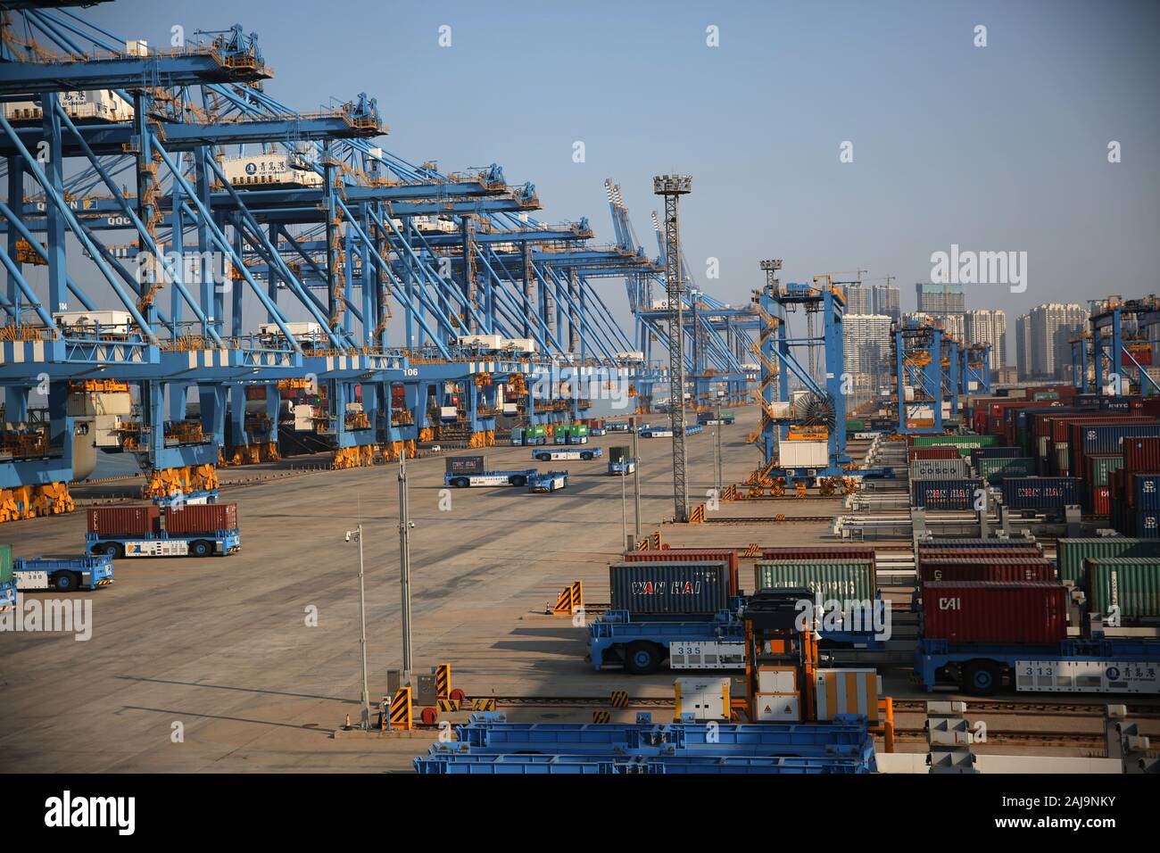 Les contenants sont levées par des grues de camions téléguidés pour être chargés sur un navire sur un quai du port de Qingdao en Qingdao City, Shandong en Chine de l'Est Banque D'Images