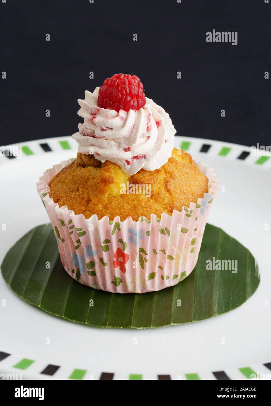 Cup Cake en cas de papier avec décoration de framboise sur le dessus, sur une feuille de bananier. Banque D'Images