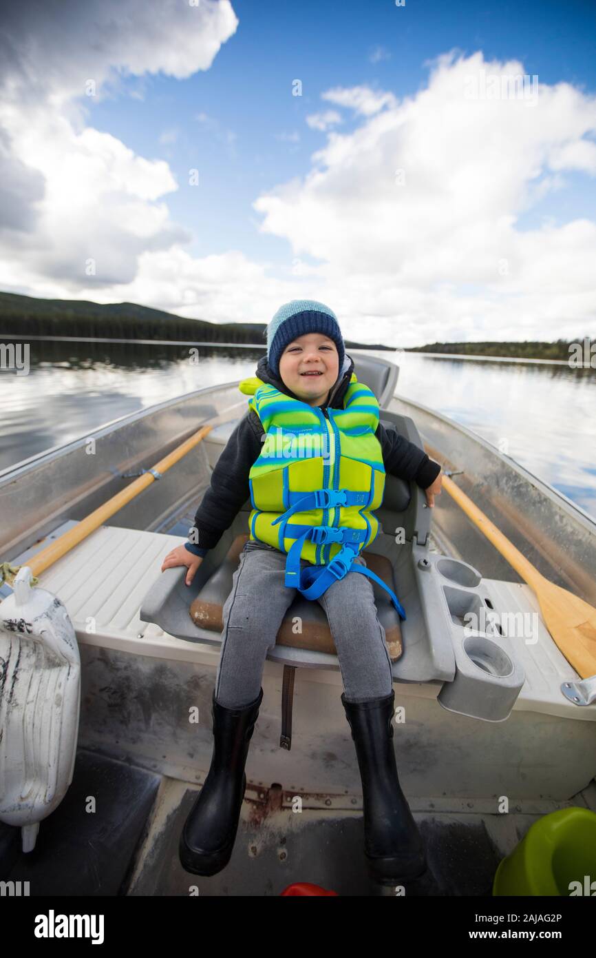 Jeune garçon assis dans un bateau en aluminium pendant la pêche. Banque D'Images