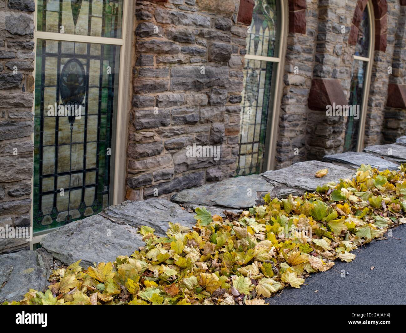 Une ligne de feuilles mortes Allée Pierre le long d'un mur de l'Église Banque D'Images