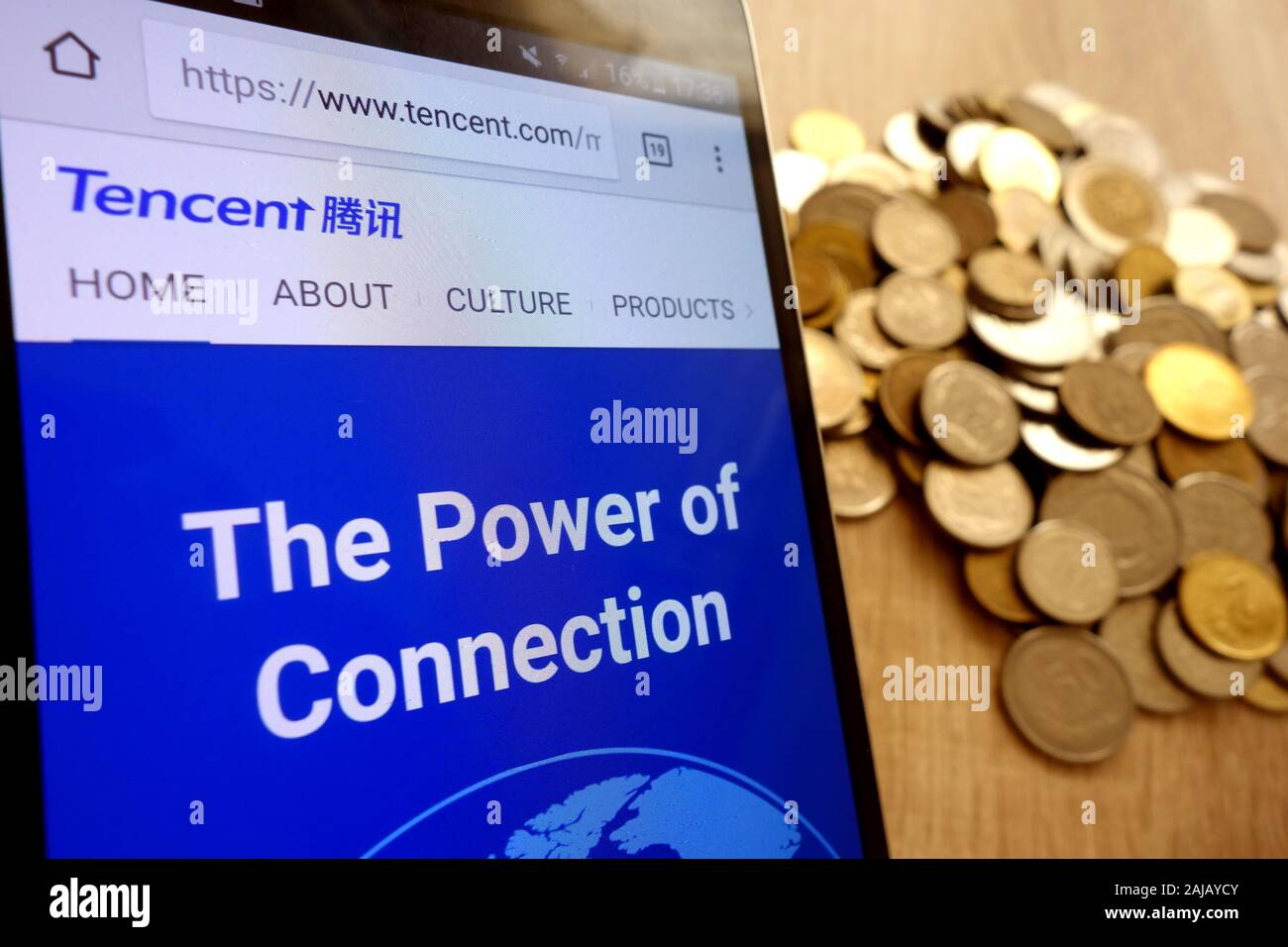 Site web de Tencent affichée sur smartphone et pile de pièces Banque D'Images
