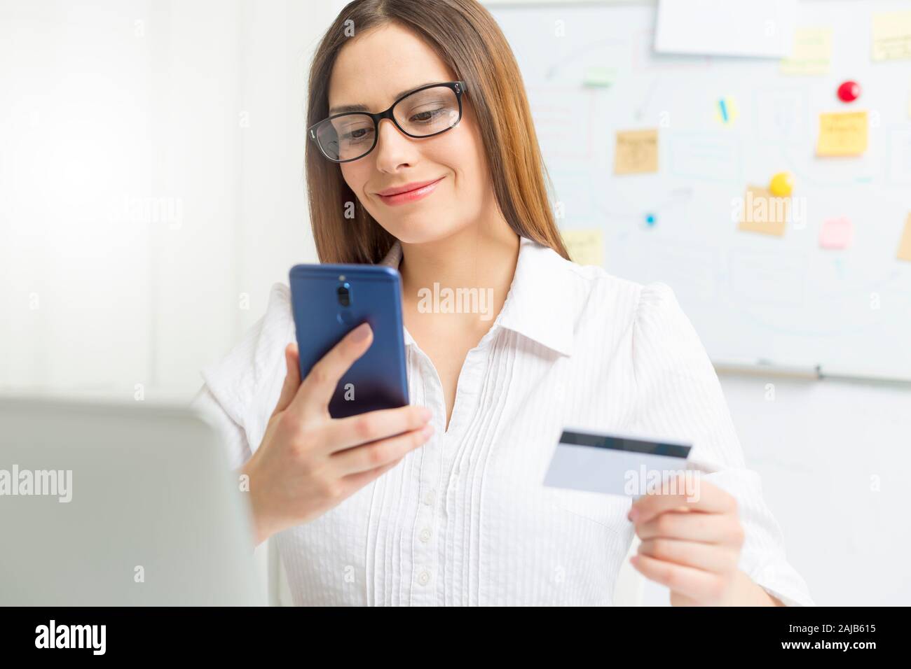 Jeune femme d'affaires utilise un téléphone mobile et une carte de crédit pour un paiement en ligne. Banque D'Images
