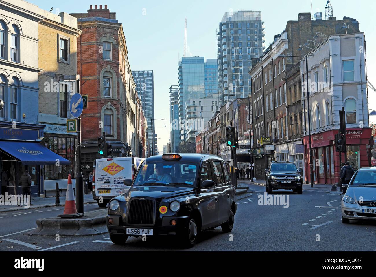 Taxi noir longeant la rue commerciale dans la circulation de Spitalfields Dans le East End Londres E1 Angleterre KATHY DEWITT Banque D'Images