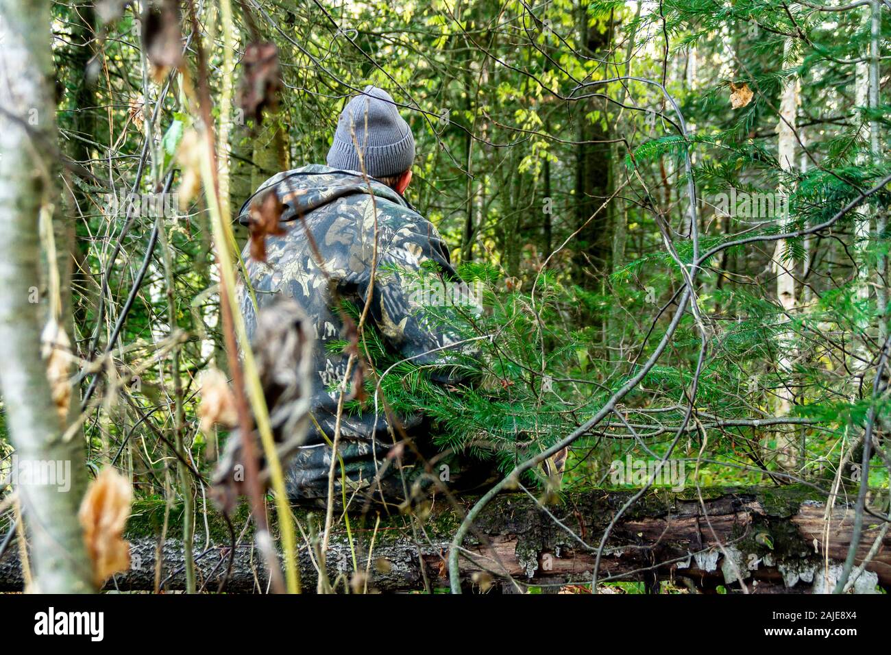 Dans les bois un homme en tenue de camouflage est assis sur un journal Banque D'Images