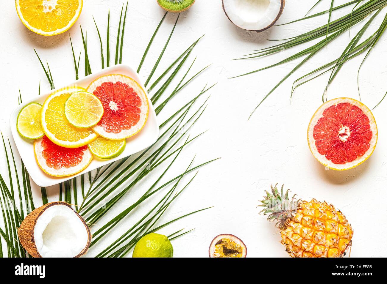 Les fruits tropicaux et de feuilles de palmier sur un fond blanc, vue du dessus. Banque D'Images