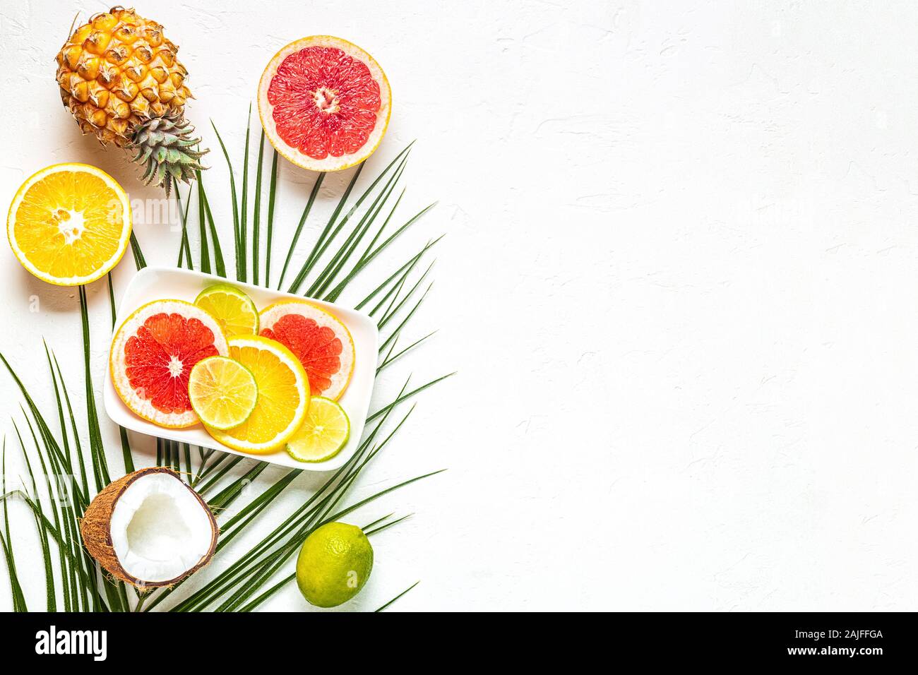 Les fruits tropicaux et de feuilles de palmier sur un fond blanc, vue du dessus. Banque D'Images