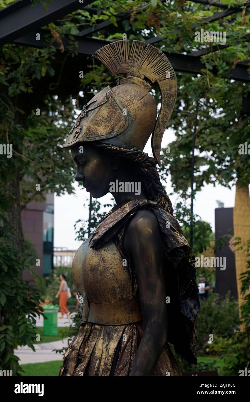 Timisoara, Roumanie- 09.06.2019 Living statue de Pallas Athéna. Femme vêtue de robe de bronze portant un casque et une lance se fait passer pour un humain réaliste s Banque D'Images