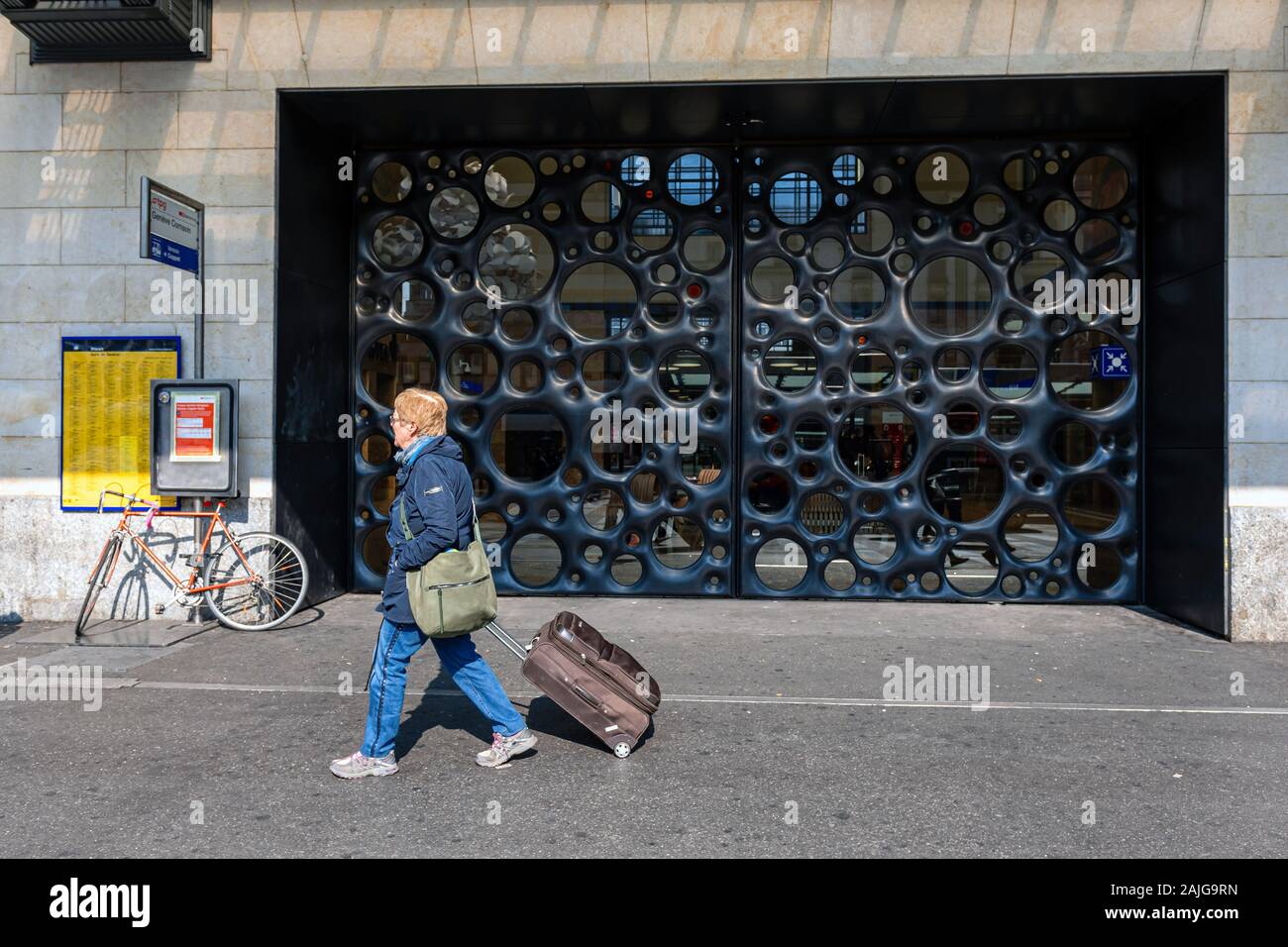 Genève, Suisse - le 14 avril 2019 : une femme avec un sac de voyage passe devant la porte principale de la gare la gare de Cornavin - image Banque D'Images