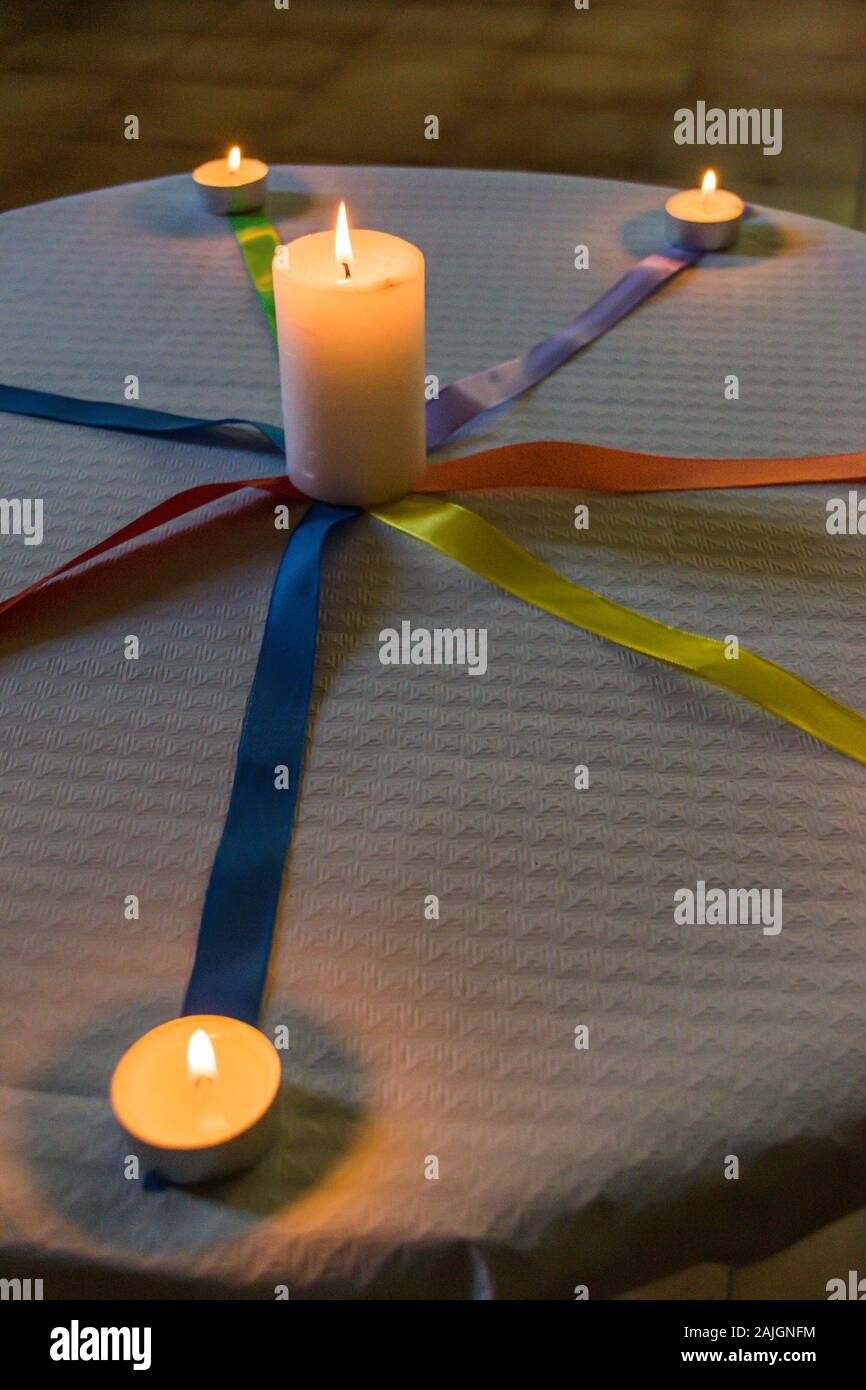 Bougies avec des liens de couleur sur une table avec nappe en papier blanc Banque D'Images