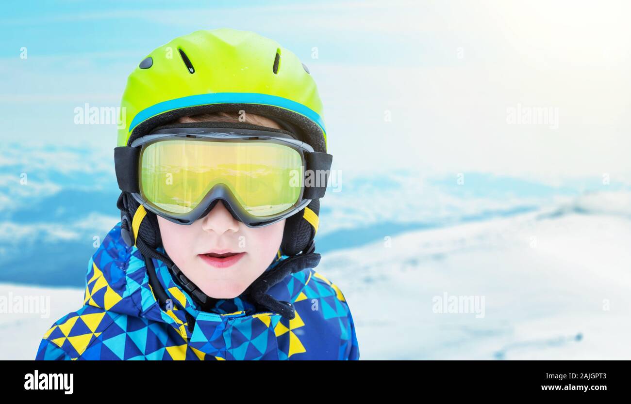 Garçon fashion portrait moderne avec matériel de ski sur la station de ski. Des sommets enneigés en arrière-plan. À côté de l'espace de copie Banque D'Images