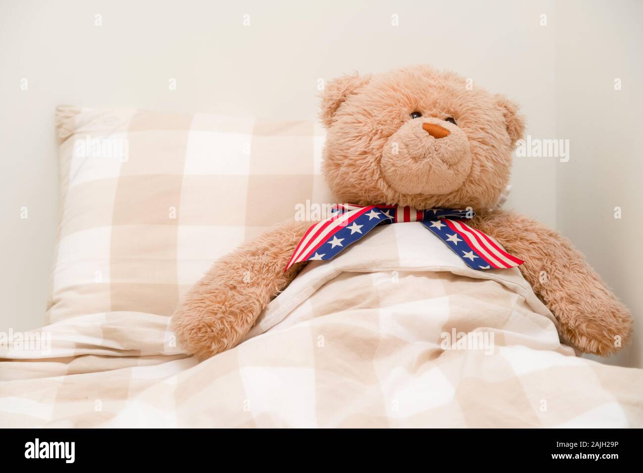 Ours dormir dans un lit avec le drapeau américain à égalité. Peluche dans des couvertures sur le jour de l'indépendance Banque D'Images
