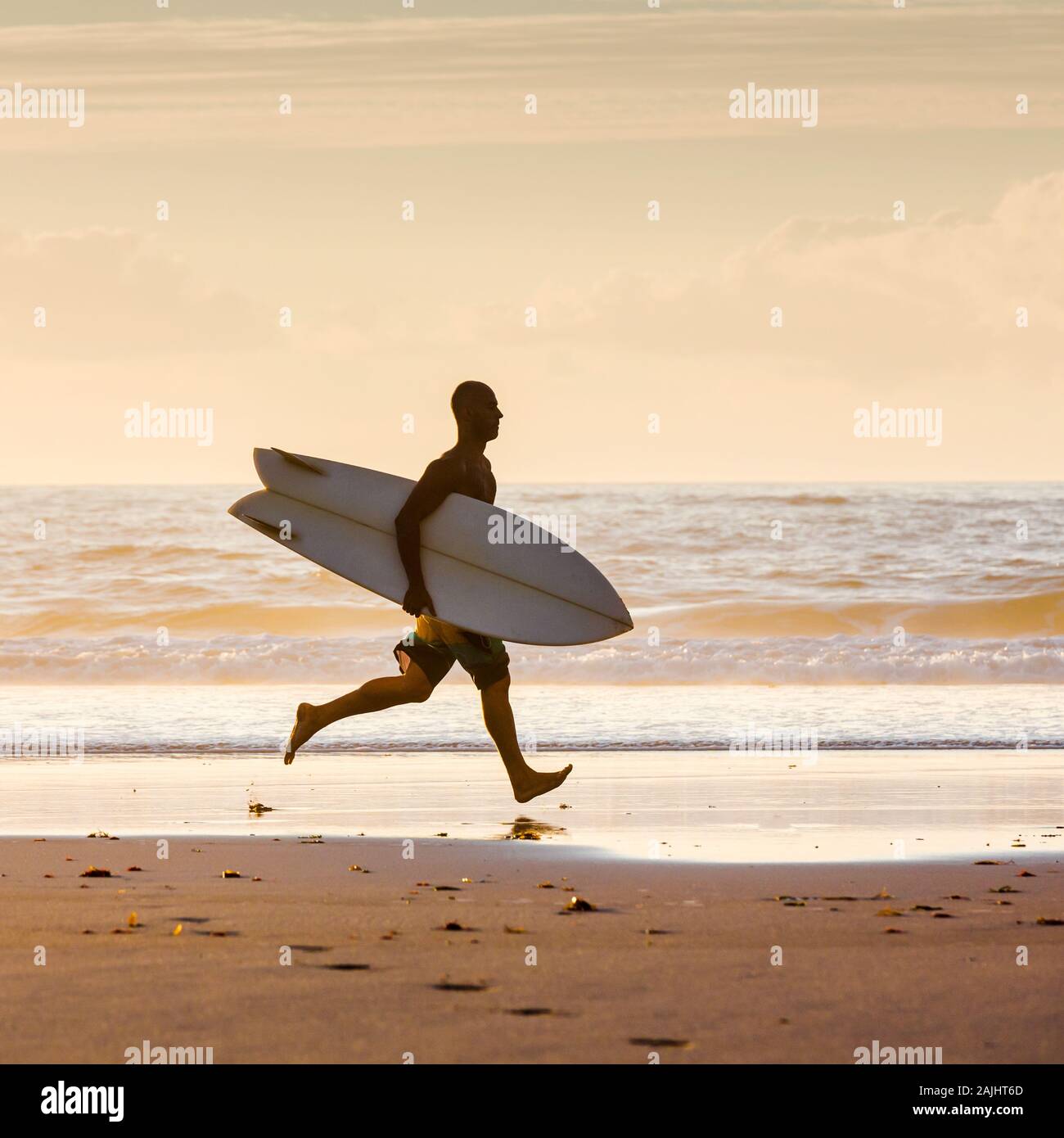 Surfeur sur la plage en cours d'exécution avec surfbard est prêt à naviguer Banque D'Images